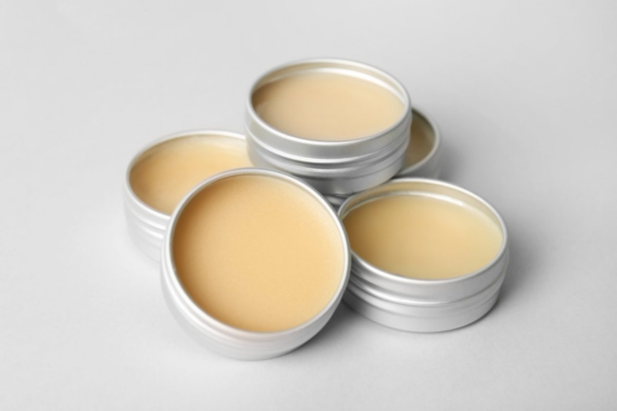 Open tins of lip balm ointment on a light gray background
