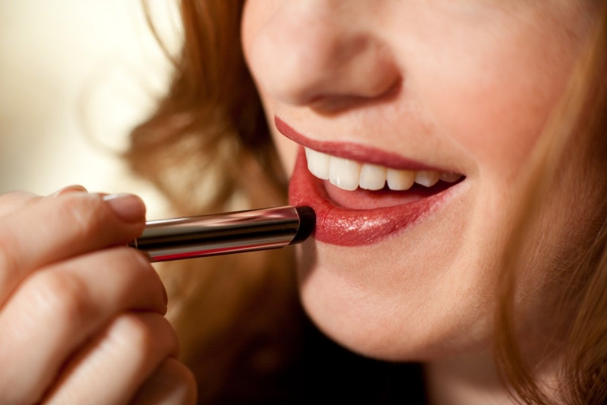 Close-up of a woman applying red lipstick